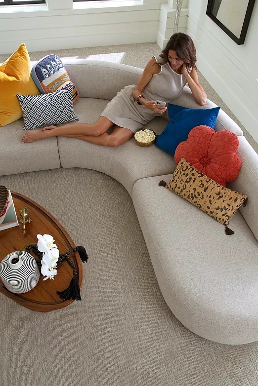 woman lounging on a gray couch on taupe carpet