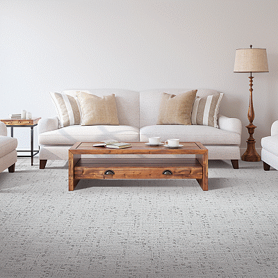 A cream couch and wood coffee table on carpet